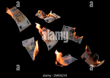 Verbrennen von Geld, zwanzig und fünfzig Euro-Banknoten mit isolierten Flammen vor schwarzem Hintergrund, Konzept für Inflation, Finanzen, Investitionsrisiko Stockfoto