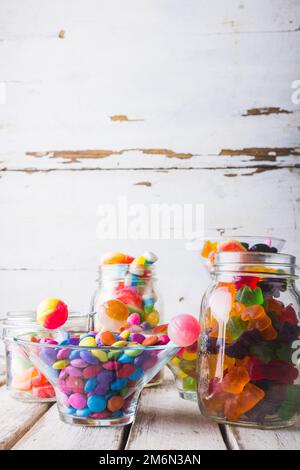 Nahaufnahme von mehrfarbigen Bonbons und Lutschern in Gläsern und Schüssel auf dem Tisch Stockfoto