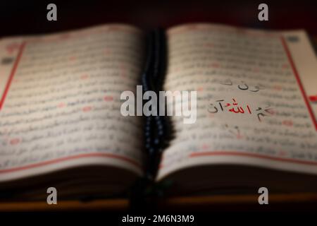 Allah-Text über den Heiligen Koran im Fokus. Unscharfer Hintergrund. Hintergrundbild aus Ramadan oder Islamic. Stockfoto