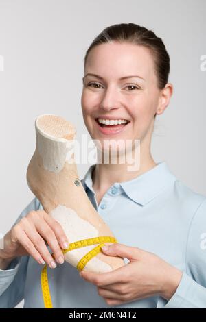 Eine junge Schuhmacherin, die ein individuell gefertigtes Letztes präsentiert Stockfoto