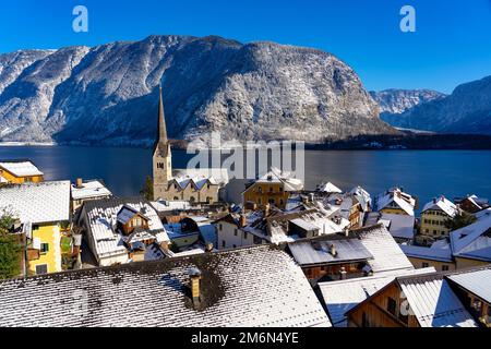 Wunderschönes Stadtbild der besonderen Stadt Hallstatt in Österreich Salzkammergut verschneite Winterberge und See und Kirche. Stockfoto