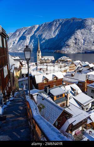 Wunderschönes Stadtbild der besonderen Stadt Hallstatt in Österreich Salzkammergut verschneite Winterberge und See und Kirche. Stockfoto