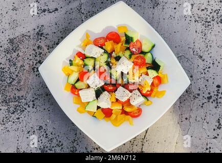 Frischer griechischer Gemüsesalat mit Kirschtomaten, Paprika, Gurke, Fetakäse, Olivenöl und Gewürzen der Saison, gesunder Foos Stockfoto