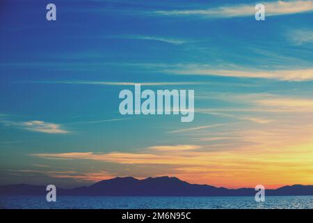 Meereslandschaft mit Bergen bei Sonnenuntergang. Rockies am Abend. Blick auf den Olymp am Horizont. Wunderschöne Natur Griechenlands Stockfoto