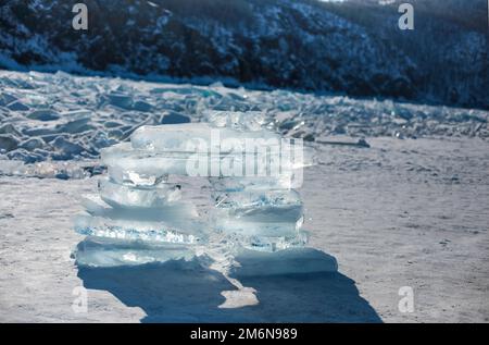 Eisstücke liegen auf dem idealen glatten Eis von baikal mit Eishummocks am Horizont Stockfoto