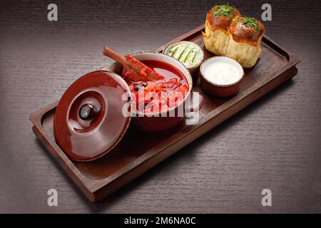 Ukrainischer Borschtsch mit Schweinerippchen, Sauerrahm und Knoblauchbrötchen Stockfoto