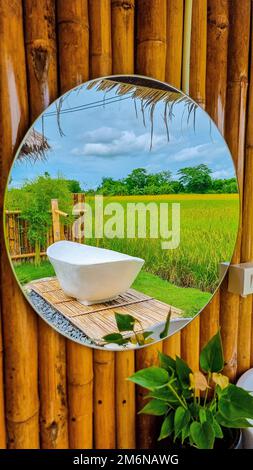 Weiße Badewanne draußen im Urlaub in einer Gastfamilie in Thailand mit grünem Reisfeld Stockfoto