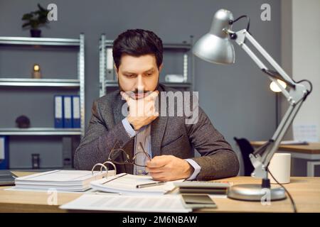 Junger Geschäftsmann, Rechnungsprüfer oder Finanzbuchhalter, der im Büro Papierkram erledigt Stockfoto