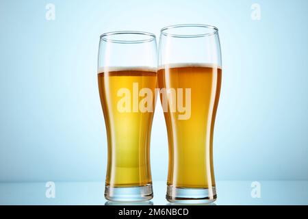 Glitzerndes gelbes Bier, das in hohe Gläser auf hellblauem Glas gegossen wurde. Stockfoto