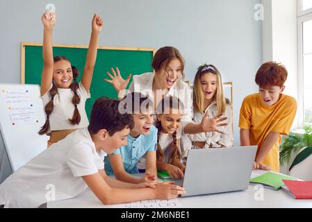 Eine Gruppe glücklicher Kinder und Lehrer, die ihren Laptop benutzen und Spaß im Unterricht haben Stockfoto