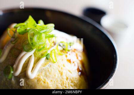 Japanisches Reisomelett gefüllt mit Gemüse, Fleisch und verschiedenen Saucen. Stockfoto