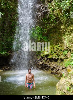 Junge Männer entspannen sich im Toraille Wasserfall St. Lucia. Dschungel-Wasserfall St. Lucia und Männer schwimmen Stockfoto