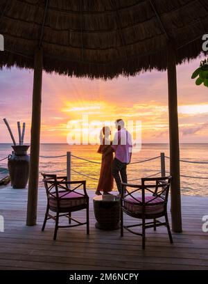 Ein Paar trinkt Cocktails während des Sonnenuntergangs am tropischen Strand von Saint Lucia oder St. Lucia Caribbean Stockfoto
