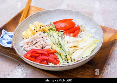 Hiyashi Chuka ist eine japanische kalte Ramen-Nudeln, gemischt mit hausgemachtem Dressing und garniert mit Ei, Imitationen von Krabben, Schinken, Gurken und Tomaten. Stockfoto