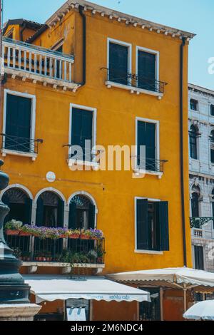 Ein vertikales Bild der Fassade eines wunderschönen alten gelben Gebäudes in Venedig Italien an einem sonnigen Tag Stockfoto