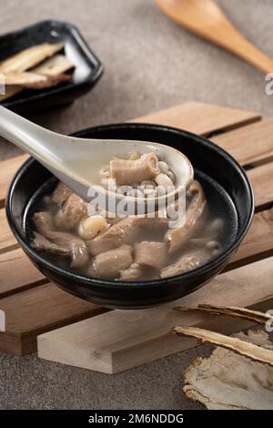 Four Tonics Suppe. Köstliches hausgemachtes taiwanesisches traditionelles chinesisches Kräutergericht mit Kräutern, Schweinedärm auf grauem Tischhintergrund Stockfoto