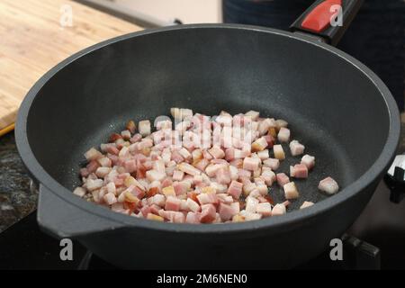 Roher Speck in der Pfanne frittieren, um Grieben zu machen. Stockfoto