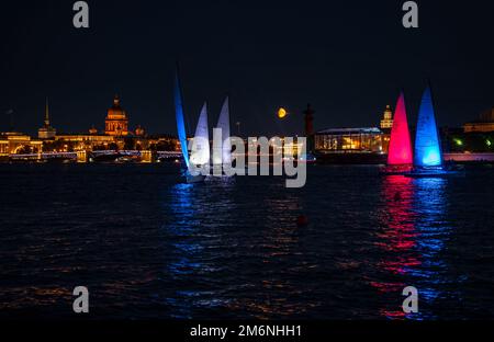 Russland, St. Petersburg, 07. August 2022: Einige Segelboote mit beleuchteten Segeln in der Tricolor von Russland fahren in das Stadtzentrum A Stockfoto