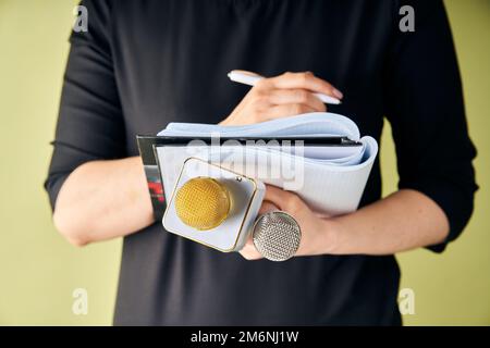 Journalistin auf der Pressekonferenz, schreibt Notizen und hält Mikrofon Stockfoto