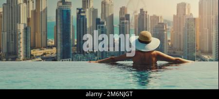 Frau genießt die Skyline des Yachthafens von Dubai vom luxuriösen Hotel Infinity Pool aus. Banner mit Kopierbereich Stockfoto