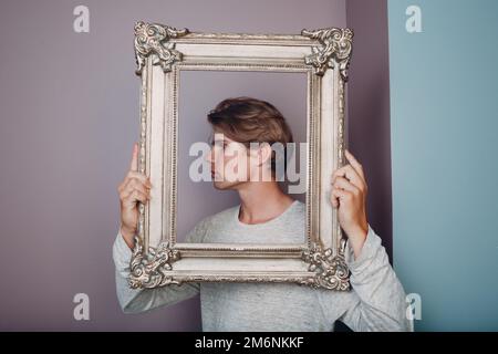 Portrait junger Mann, der im Studio mit Bilderrahmen steht. Stockfoto