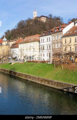 Häuser am Ufer des Flusses Ljublijanica in Ljubliana mit Burg im Hintergrund. Slowenien. Stockfoto