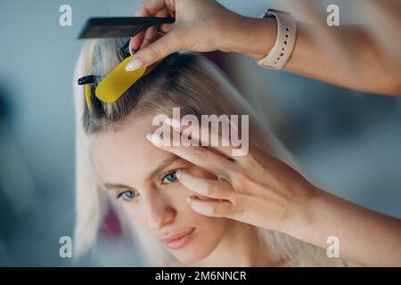 Friseur Frau macht Haarerweiterungen für junge Frau mit blonden Haaren im Schönheitssalon. Professionelle Haarverlängerung. Stockfoto