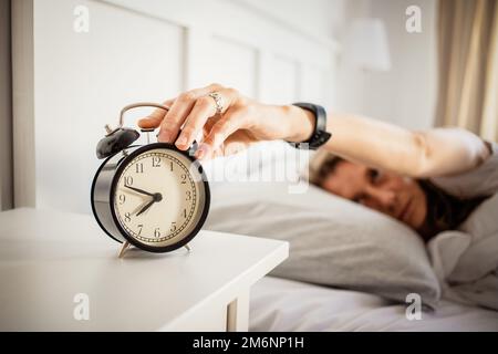 Wecker und Frau, die im Bett schläft, gute Schlafqualität Stockfoto