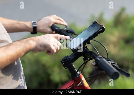 Mann plant Route mit GPS-Navigations-Anwendung im Handy auf seinem Fahrrad. Stockfoto