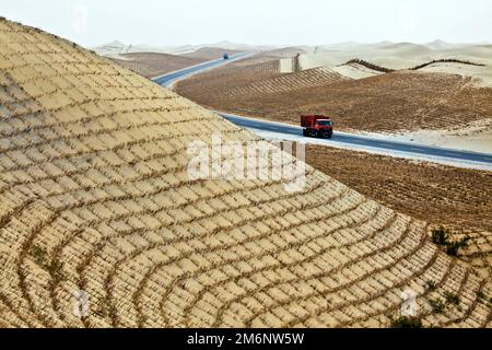 Stroh gepflanzt, um zu verhindern, dass sich der Wüstensand von Taklamakan auf Straßen und Wohngebiete verlagert. Tarim-Becken. Autonome Region Xinjiang (Sinkiang) Stockfoto