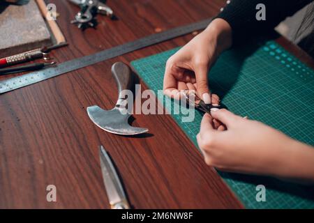 Tanner Frau, die in der Werkstatt Lederwaren anstellt. Arbeitsprozess des Lederhandwerks Stockfoto