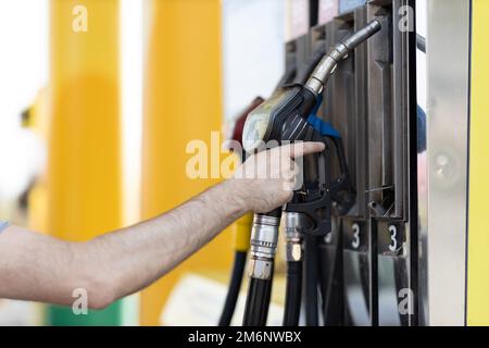 Ein Mann mit Füllpistole in der Hand an der Tankstelle Stockfoto