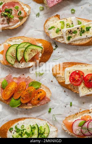 Verschiedene kleine Sandwiches mit Frischkäse, Gemüse und Salami. Stockfoto