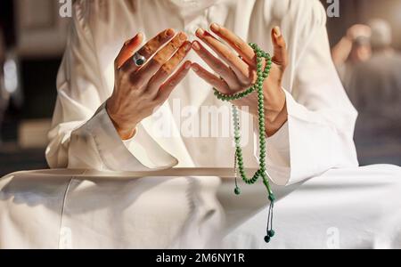 Hände, Gebetsperlen und muslimischer Mann, der in Moschee, Tempel oder Kirche betet. Islam, Gottesdienst und islamischer Mann mit Perlen dafür, Allah, Gott oder Heilig zu verehren Stockfoto