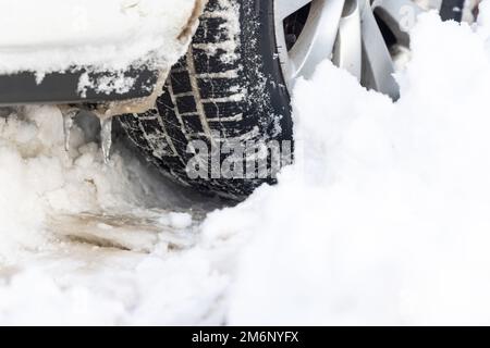Nahaufnahme von PKW-Reifen im Winter auf der Straße mit Schnee bedeckt Stockfoto