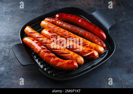 Traditionelle deutsche Bratwurstwurst in einer rustikalen Bratpfanne aus Gusseisen Stockfoto