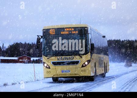 Der gelbe Volvo-Bus transportiert Passagiere im Winter/Schneefall entlang der Straße. Salo, Finnland. 28. Dezember 2022. Stockfoto