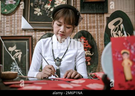 Ein junger Künstler schreibt Kalligraphie, um das neue Jahr in Ho-Chi-Minh-Stadt, Vietnam, zu feiern. Stockfoto