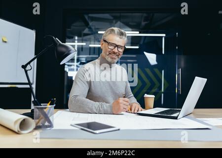 Porträt eines leitenden Architekten, grauhaariger Designer, der lächelt und in die Kamera schaut, Mann-Modell-Plan Verwenden Sie Laptop und Tablet-Computer bei der Arbeit im Studiobüro. Stockfoto