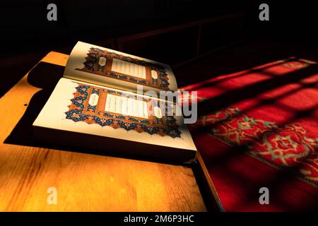 Islamisches Hintergrundfoto. Die ersten Seiten von Koran auf dem Rednerpult in der Moschee erleuchtet von Sonnenlicht. Ramadan oder kandil oder laylat al-qadr oder kadir gece Stockfoto
