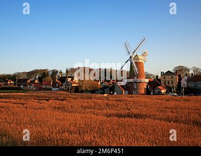 Blick auf die Windmühle und das Dorf über Schilfbetten an der Nordnorfolkküste in Cley Next the Sea, Norfolk, England, Großbritannien. Stockfoto