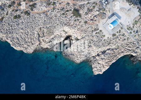 Drohnenaufnahme der Halbinsel Cape Greco mit der Agioi Anargyroi Kirche auf den Felsen. Türkisfarbenes Meerwasser Stockfoto