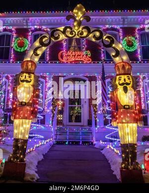 Blechsoldaten bewachen den Eingang zu einem wunderschön beleuchteten Weihnachtshaus und begrüßen frohe Weihnachten an einem Winterabend in St. Croix Falls WI. Stockfoto