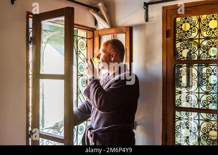 Europäischer Tourist genießt seinen morgendlichen Pfefferminztee am Fenster eines traditionellen marokkanischen Hauses in Fès, Marokko, Nordafrika Stockfoto