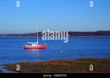 Kleines rotes Segelboot (Yacht) in der River Lune am Glasson Dock Marina in der Nähe von Lancaster in Lancashire, England, Großbritannien. Stockfoto