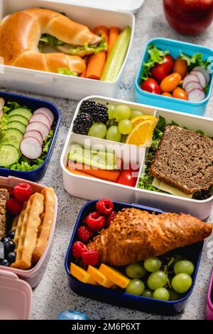 Aufnahme von Schullunchboxen mit verschiedenen gesunden, nahrhaften Mahlzeiten auf steinernem Hintergrund Stockfoto