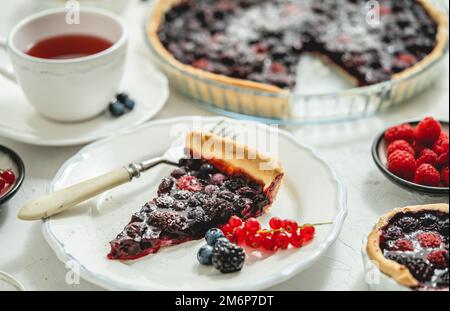 Süßes Dessert mit frisch gebackenem Waldfrucht-Pie, serviert mit Himbeer-Tee Stockfoto