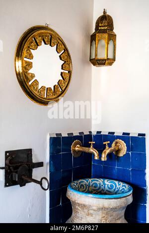 Traditionelles Waschbecken und goldener Spiegel und Lampe in der Ecke des Riad-Schlafzimmers, Medina von Fès, Marokko, Nordafrika Stockfoto