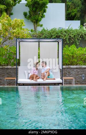 Ein paar Männer und Frauen entspannen sich auf einem Liegestuhl vor dem Swimmingpool in einem Luxusurlaub Stockfoto