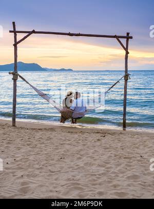 Männer und Frauen beobachten den Sonnenuntergang von einer Hängematte am Strand in Pattaya Thailand Ban Amphur Beach Stockfoto
